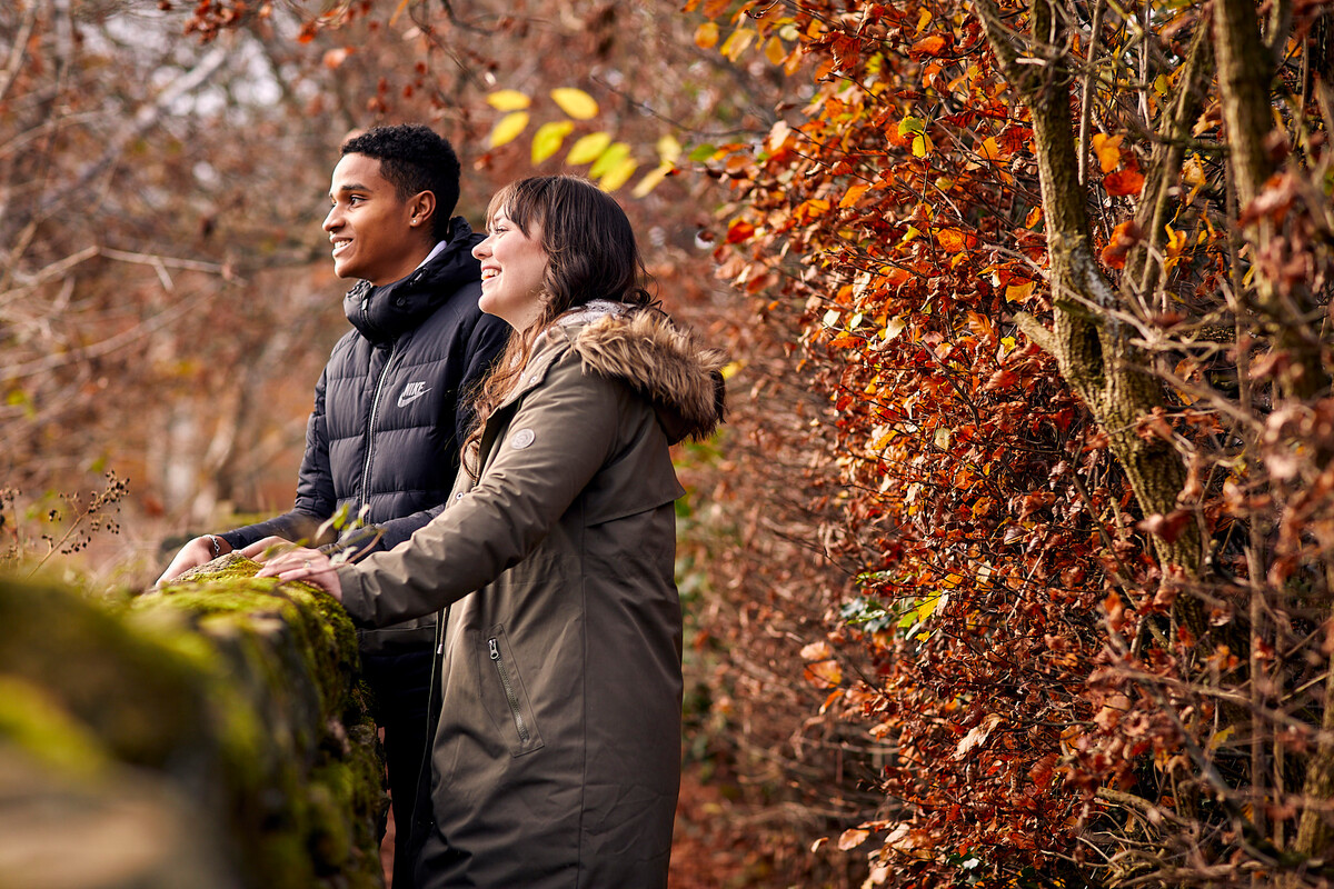 Woman and man leaning on dry stone wall and laughing