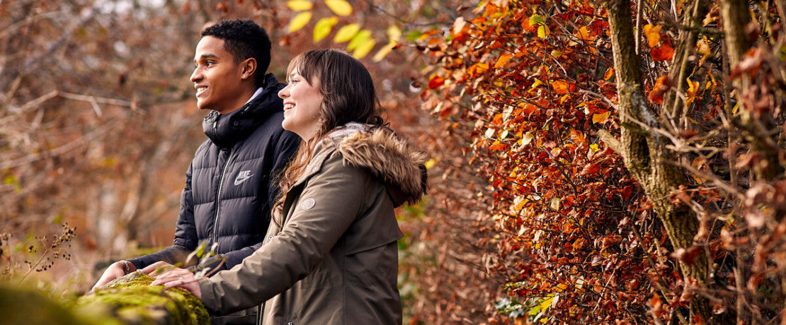 Woman and man leaning on dry stone wall and laughing