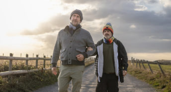 Two men walking along a rural path at sunset