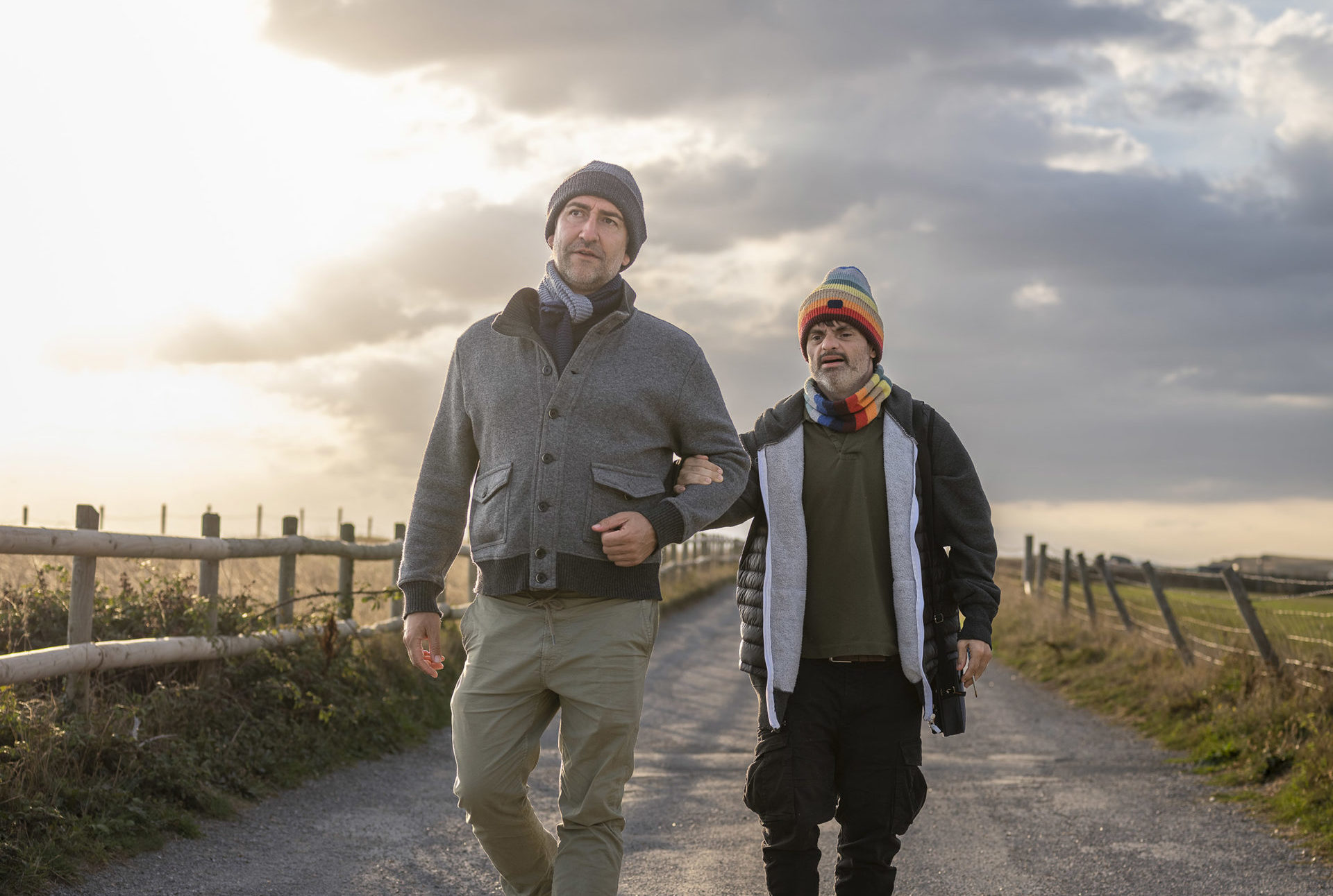 Two men walking along a rural path at sunset