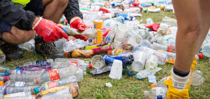 Two people handling bottles and cans litter wearing gloves