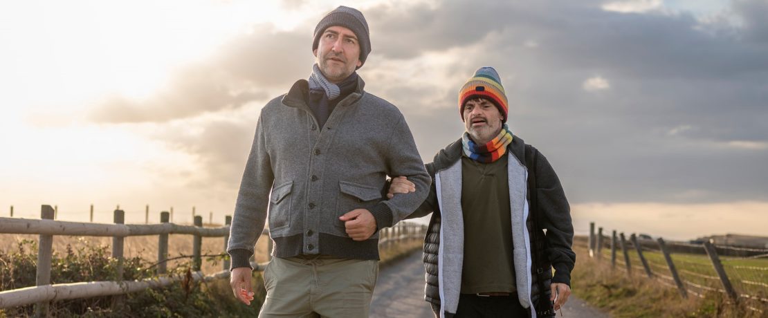 Two men walking along a rural path at sunset