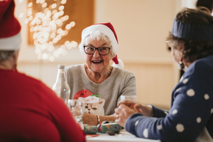 An elderley lady sat at a table during a community Christmas lunch