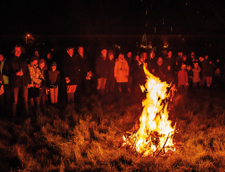 A bonfire with people stood around it