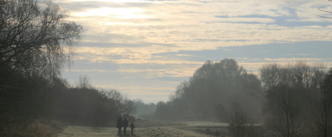 Walkers on a misty morning on fields in London green belt
