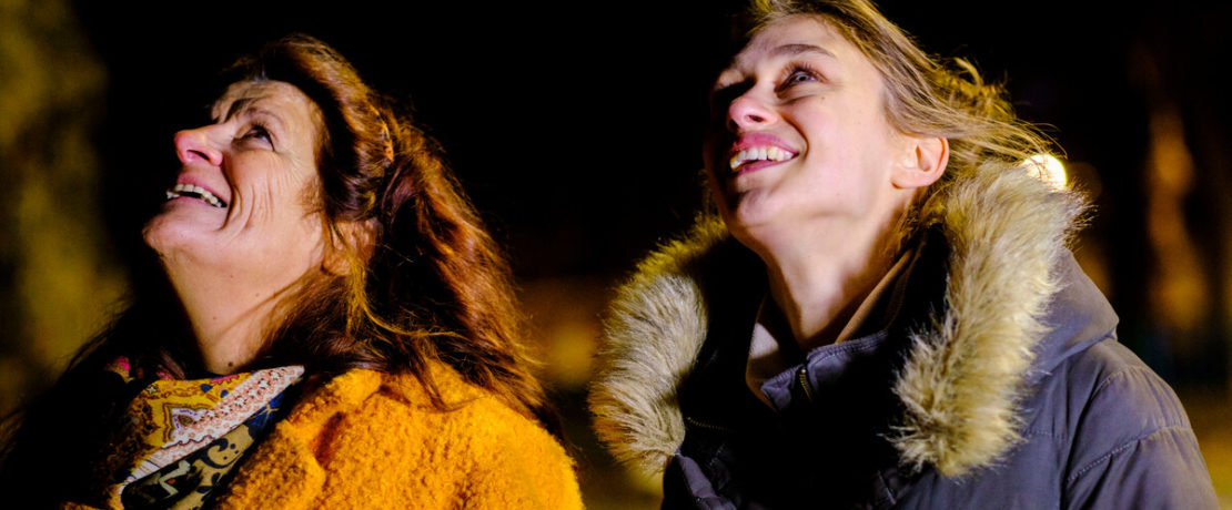 Two women smiling brightly up at the sky