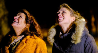 Two women smiling brightly up at the sky