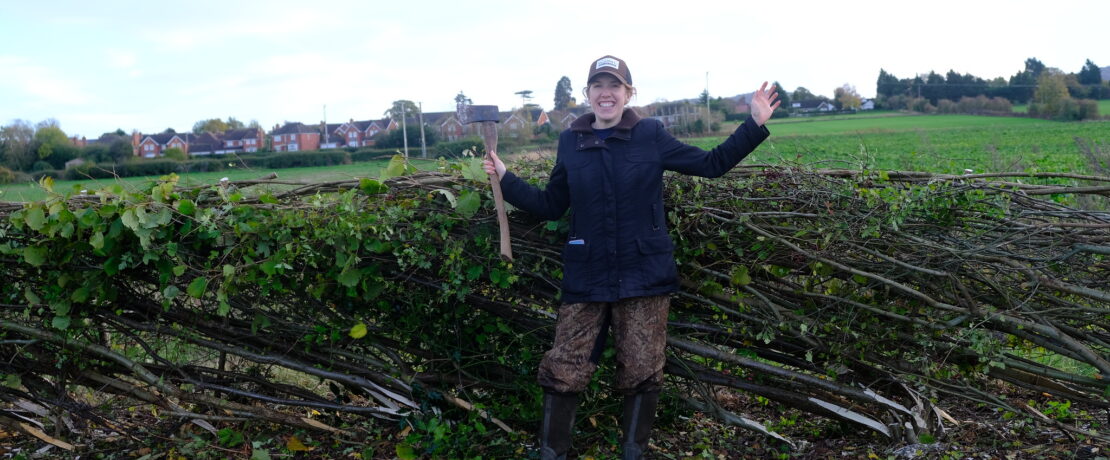 A woman stood in front of a laid hedgerow