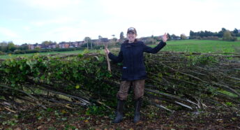 A woman stood in front of a laid hedgerow