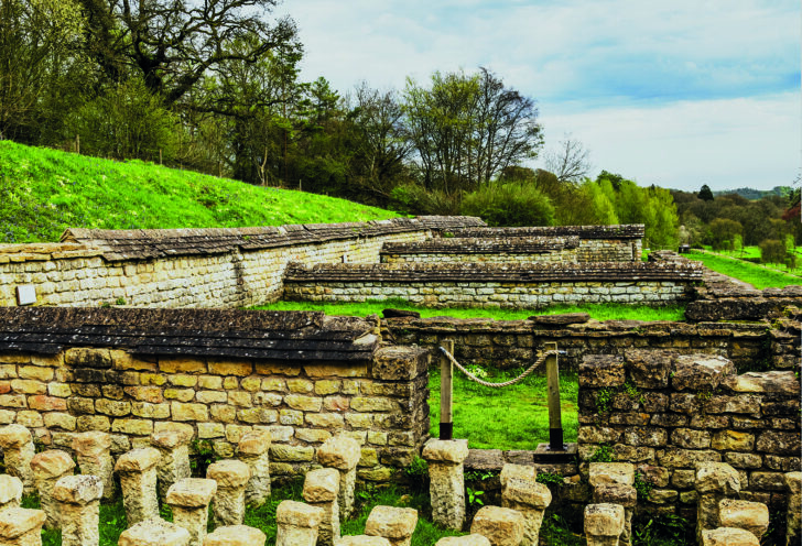 A view of Chedworth Roman Villa ruins with a series of parallel ancient walls