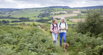 Woman and girl walking dog rolling hills
