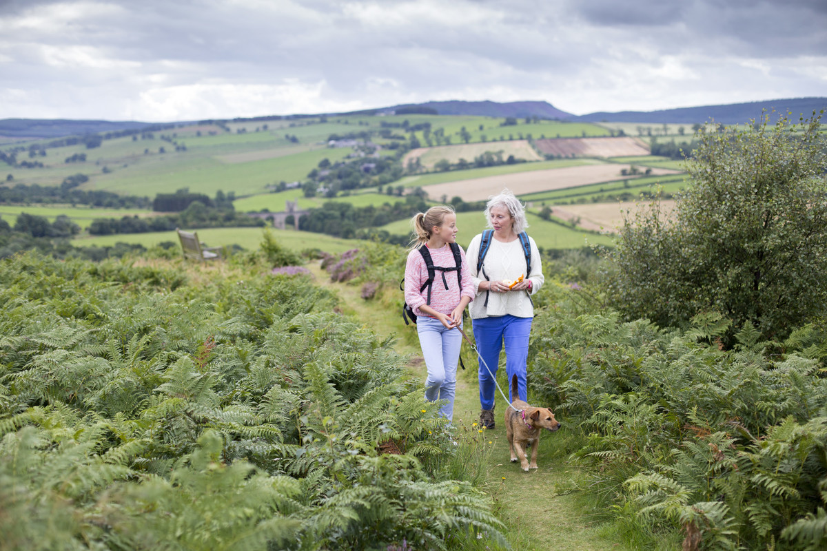 Woman and girl walking dog rolling hills