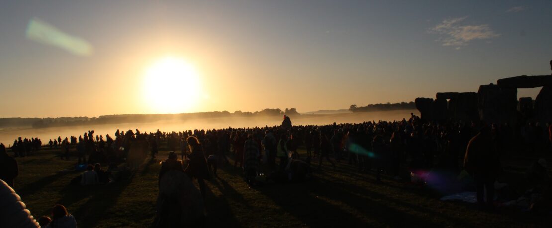 A crowd of people silhouetted against the sunset