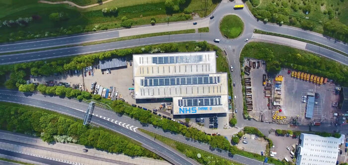 Aerial photo of solar panels on warehouse roof in between two roads