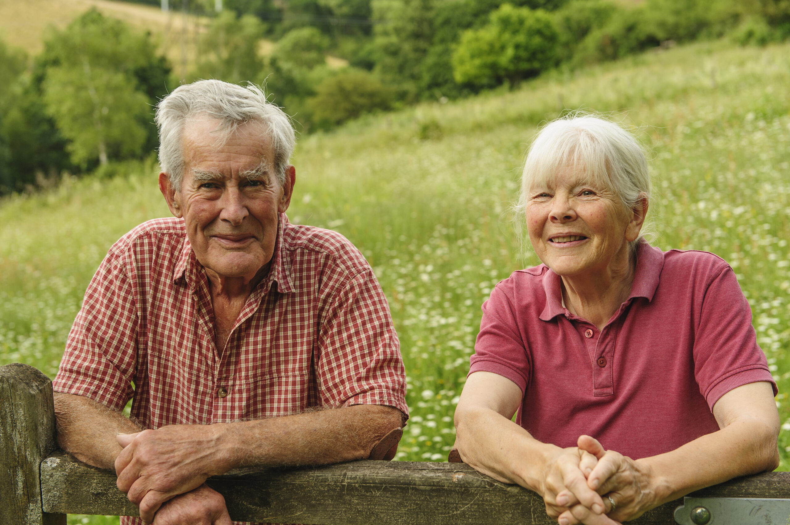 John Whetman and Audrey Compton leaning over a gate, with their wildlife rich grassland in the background