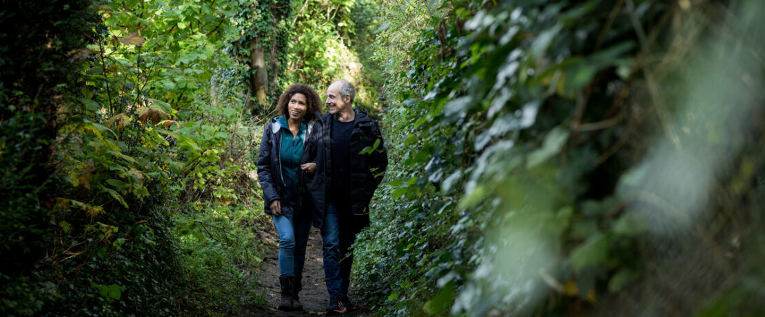 Couple walking along wooded footpath in Surrey Hills AONB