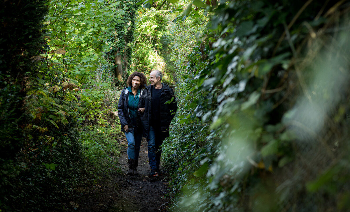 Couple walking along wooded footpath in Surrey Hills AONB