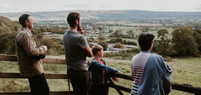 Family photos on a countryside walk leaning against a wooden gate looking out over the Green Belt