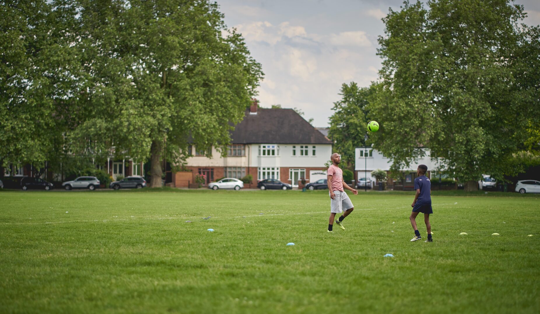 Two people playing football in a local green space