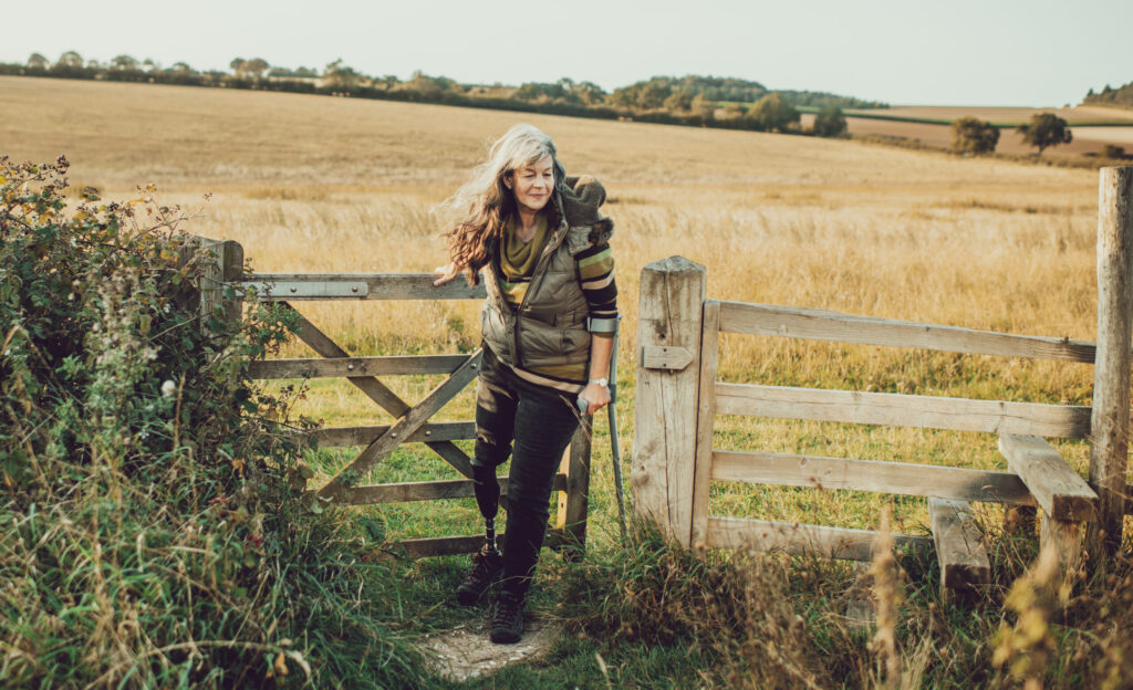 Woman with crutch coming through countryside gate