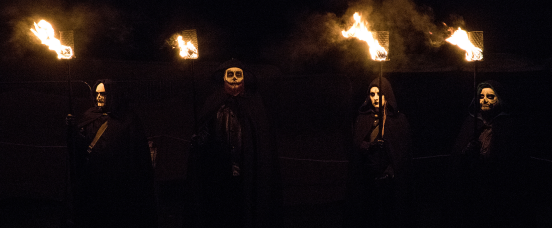 People in masks holding lit lanterns