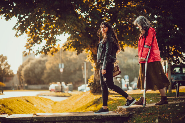 Two people walking near a tree bathed in sunlight