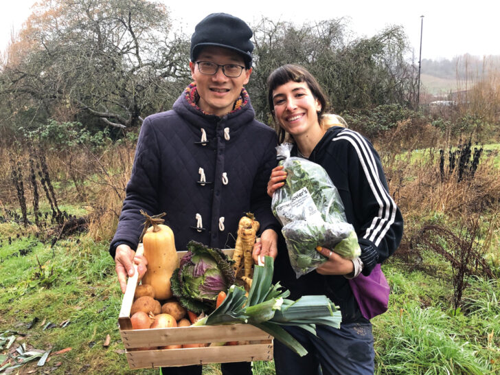 Two people with a harvest of fruits and vegetables