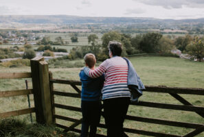 Family on a countryside walk leaning against a wooden gate looking out over the Green Belt