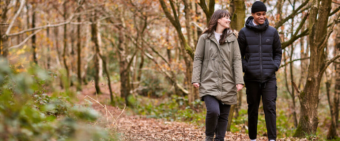 Woman and man walking through woodland and laughing