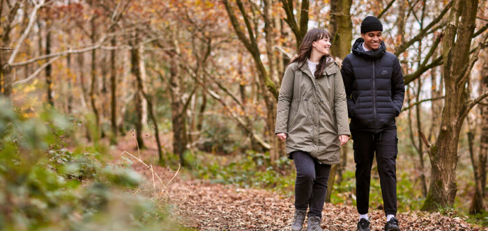 Woman and man walking through woodland and laughing