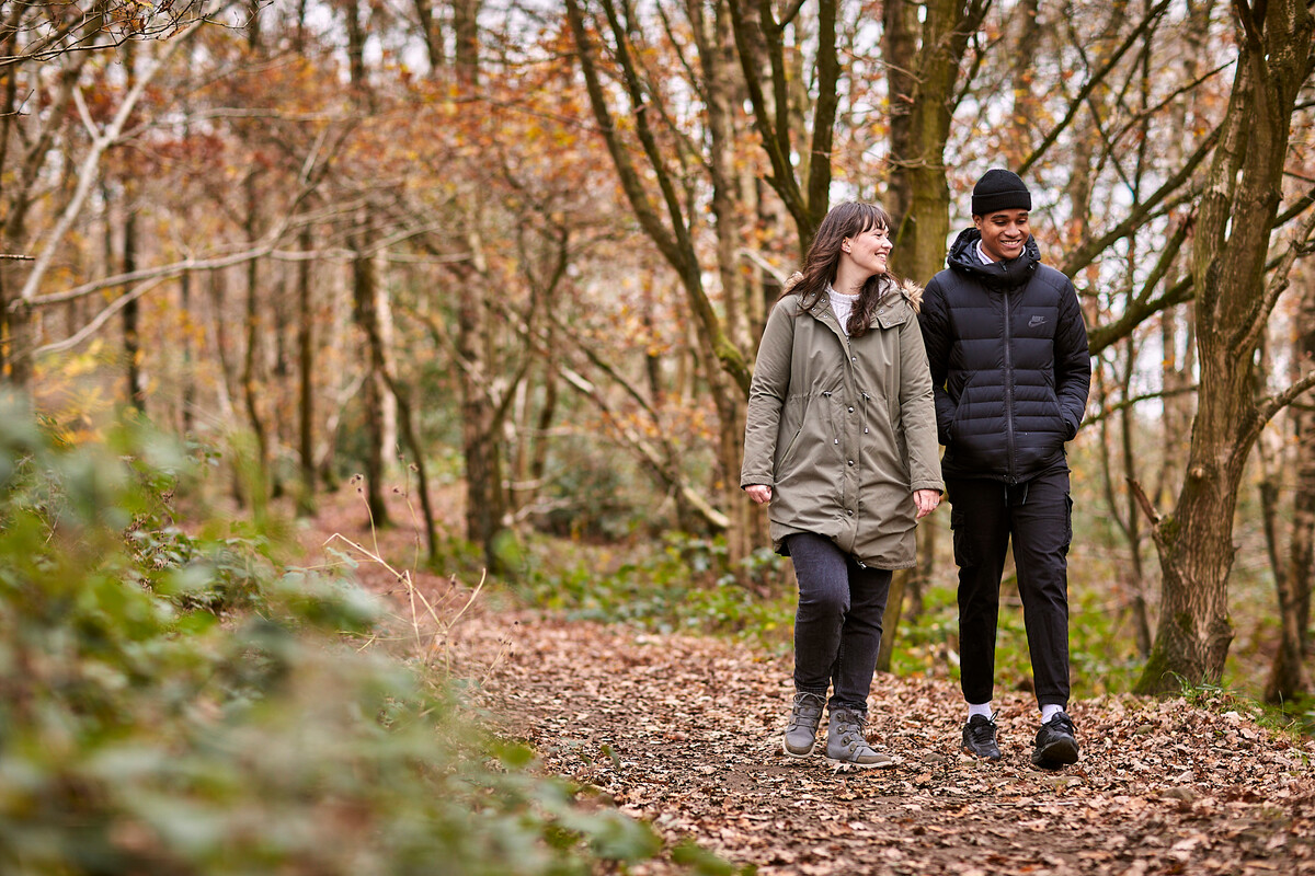 Woman and man walking through woodland and laughing