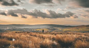 Person walking in hilly landscape with town in the distance