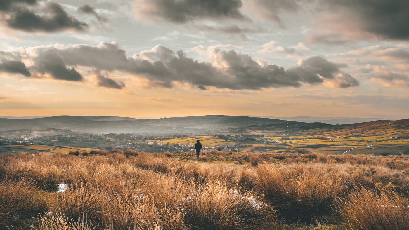 Person walking in hilly landscape with town in the distance