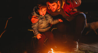 Two people looking at a fire on a dark night