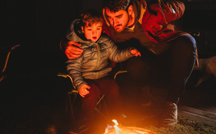 Two people looking at a fire on a dark night
