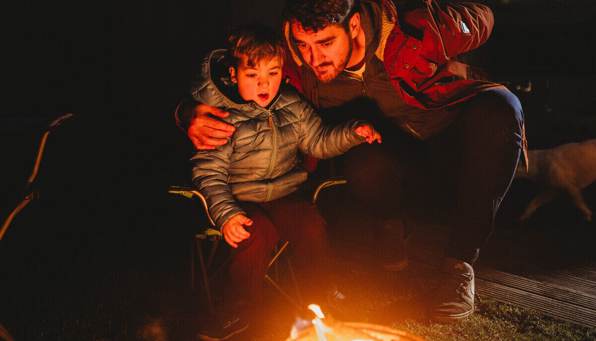 Two people looking at a fire on a dark night