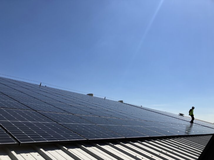 An industrial roof with solar panels on a clear blue day