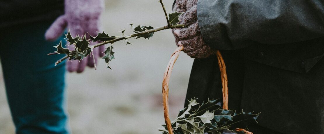 Someone passing holly to someone else from a basket