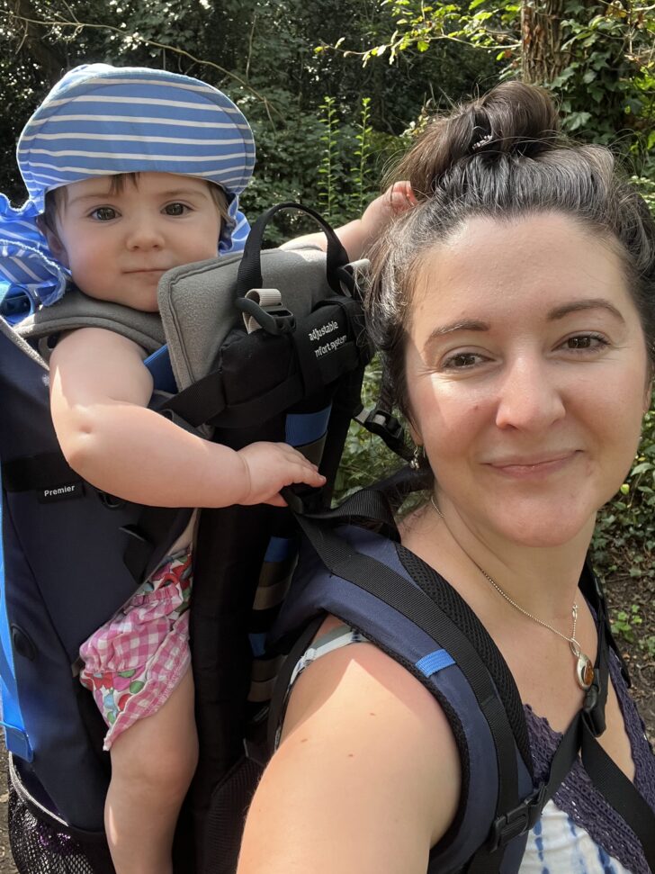 A woman and her child on her back in a carrier