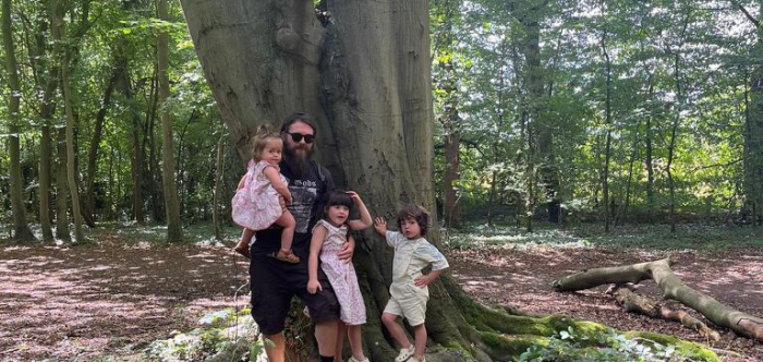 An adult and some children next to a large tree