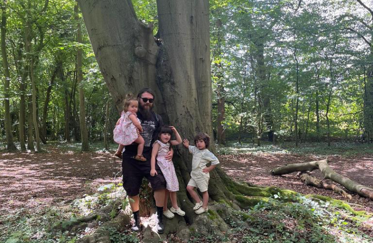 An adult and some children next to a large tree