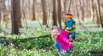 Kids playing in a winter forest with snowdrops