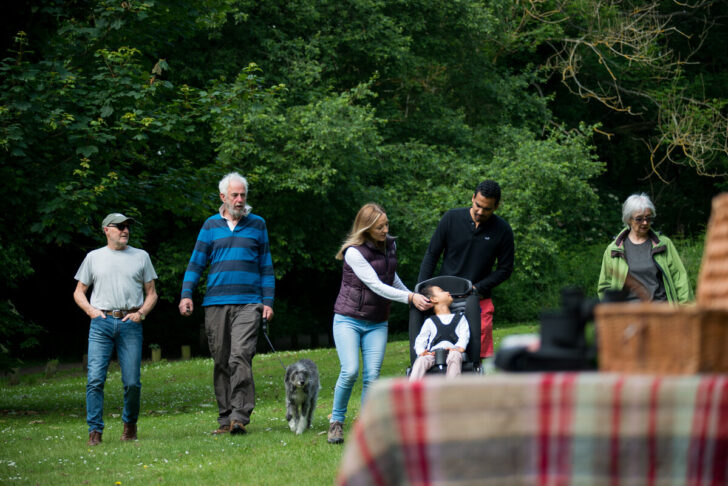 Several people including a family enjoying a picnic in green space
