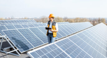 View on the rooftop solar power plant with man walking and examining photovoltaic panels. Concept of alternative energy and its service