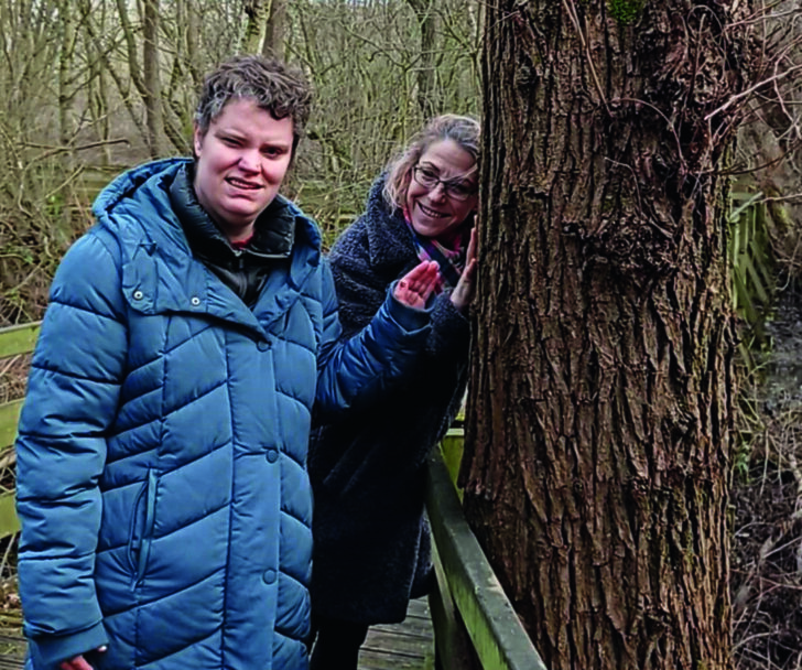 Two people leaning against a tree