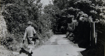 Black and white photo of Ethel Haythornthwaite walking down a country lane