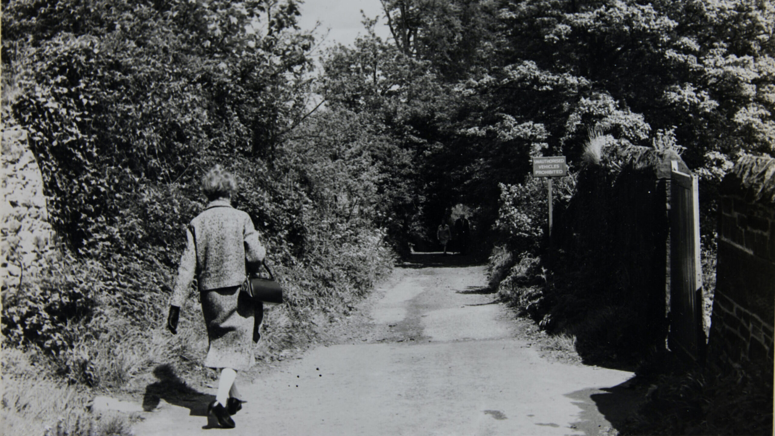 Black and white photo of Ethel Haythornthwaite walking down a country lane