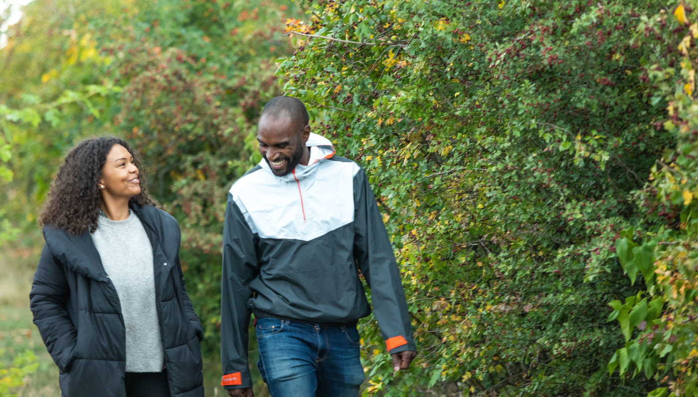 Happy couple walking along path with hawthorn hedgerow smiling