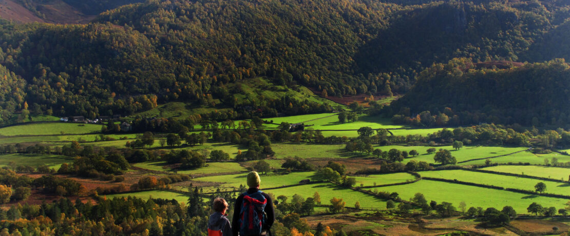A Father and son admire the view while rambling in the Lake District, Cumbria.