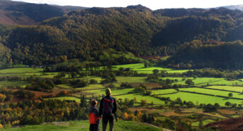 A Father and son admire the view while rambling in the Lake District, Cumbria.